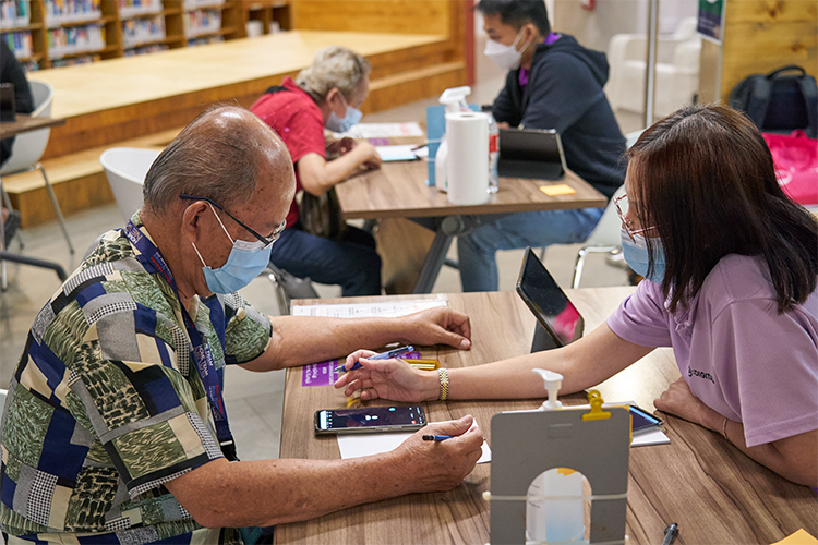 A Digital Ambassador teaching a senior how to use mobile applications (IMDA)